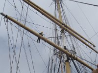 40  The National Park Service must emulate old seamen to maintain the ships. Differences: this person is female and wears a hardhat.